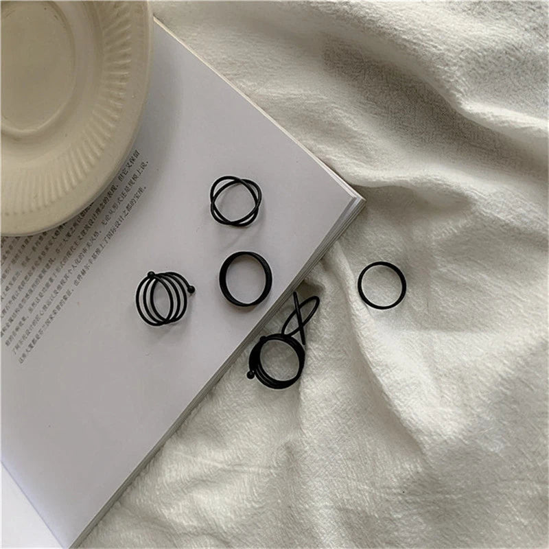 Black knuckle and finger rings laid out, including stacked and star-shaped styles