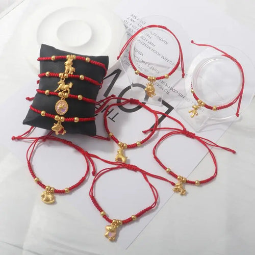Set of red rope bracelets with gold horse charms on display cards