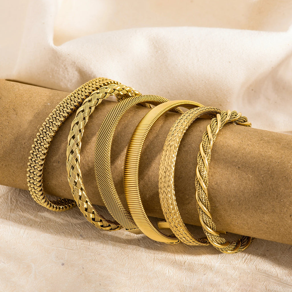 Gold open-end woven bangles with mixed textures, shown stacked on fabric