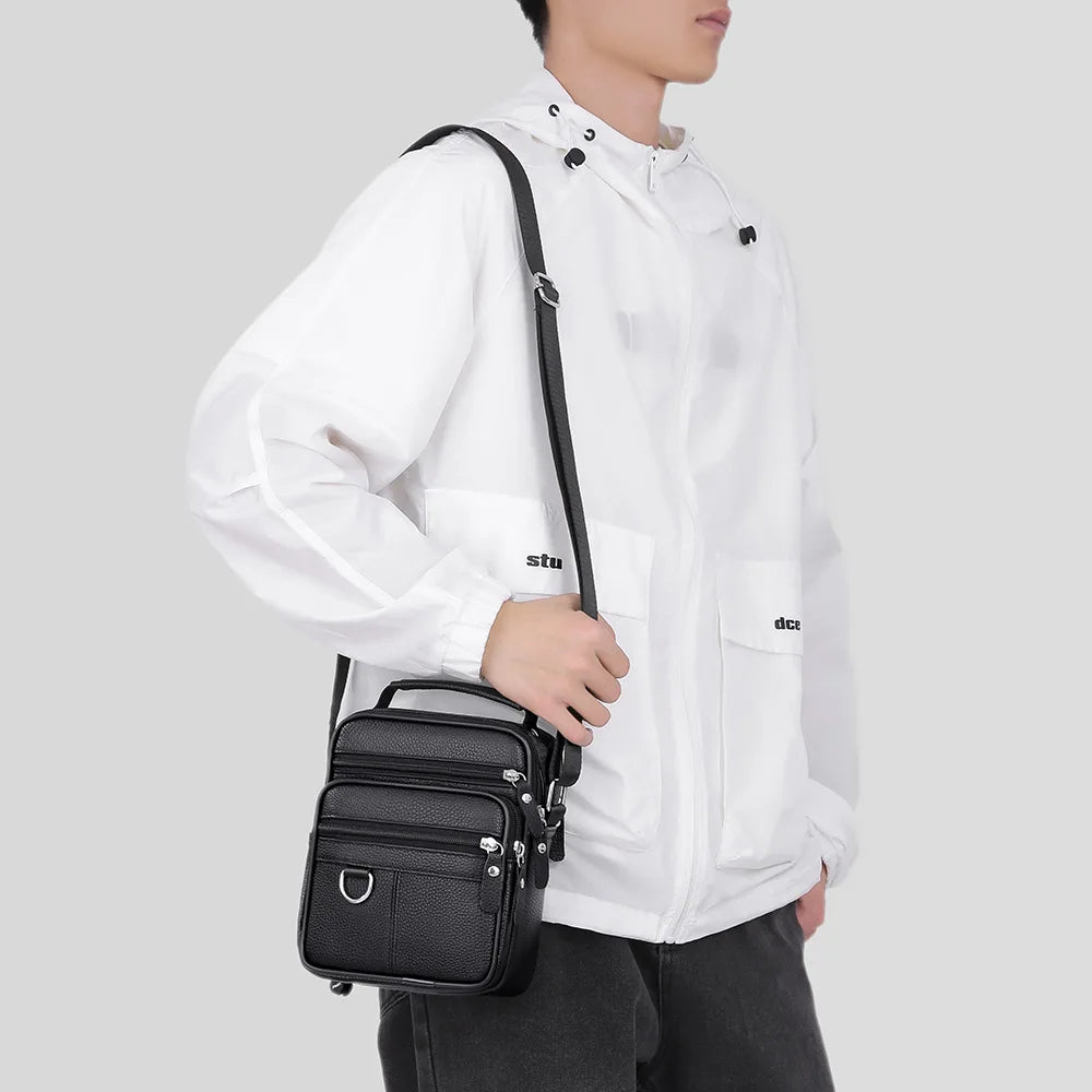Black leather crossbody bag with multiple zip pockets, worn on shoulder, adjustable strap