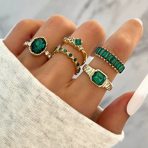 Gold-tone ring set with green oval crystal and small rhinestone bands on hand