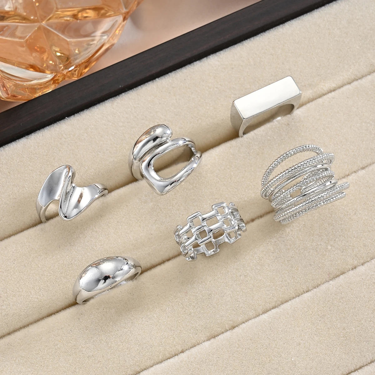 Silver-tone knuckle ring set on tray with oval sculpted and chain-link ring styles