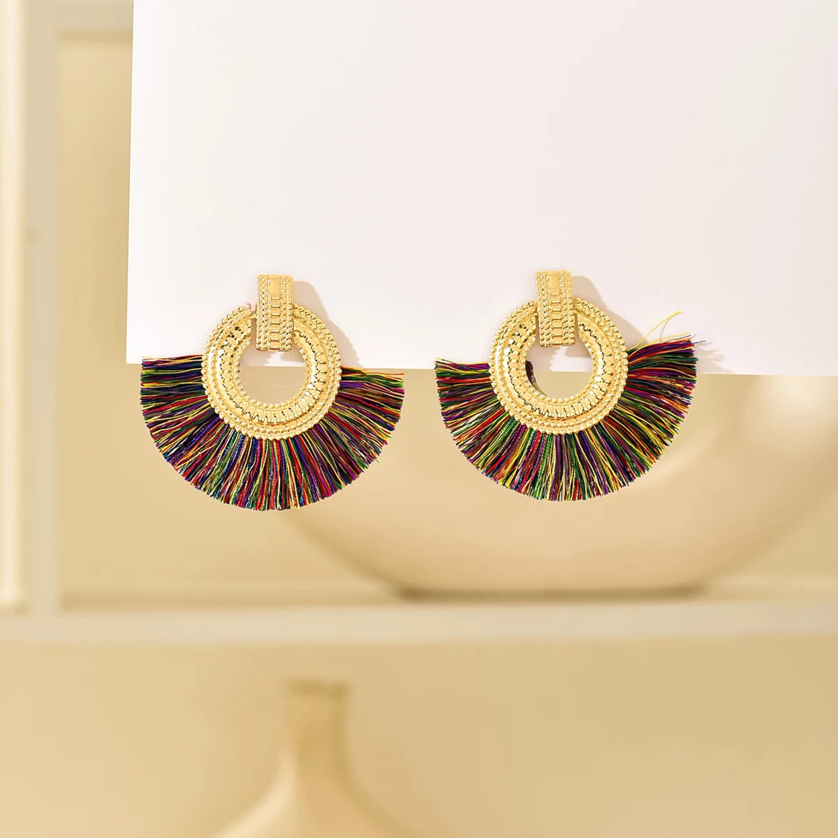 Gold fan stud earrings with multicolor tassels and circular beaded hoop outline