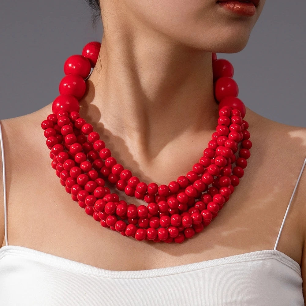Multi-layer wooden beaded necklace with red round beads worn at the collar