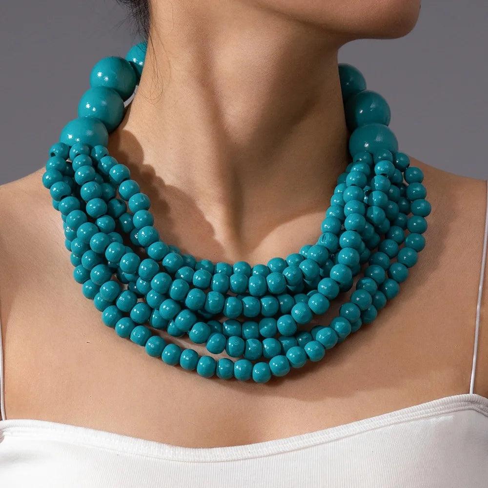 Multi-layer wooden beaded necklace with teal round beads worn close to the neck