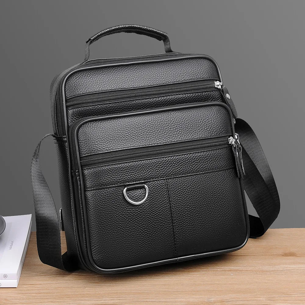 Black leather crossbody bag front view with flap pocket, two zip compartments, shoulder strap