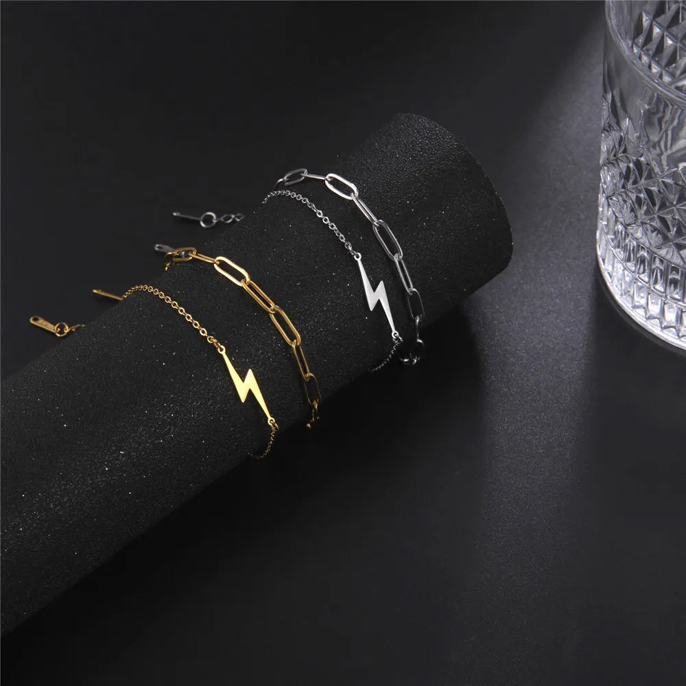 Mixed-tone lightning bolt charm bracelets on dark display
