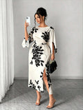 White midi dress with black floral print, long sleeves, front slit, slim fit waist
