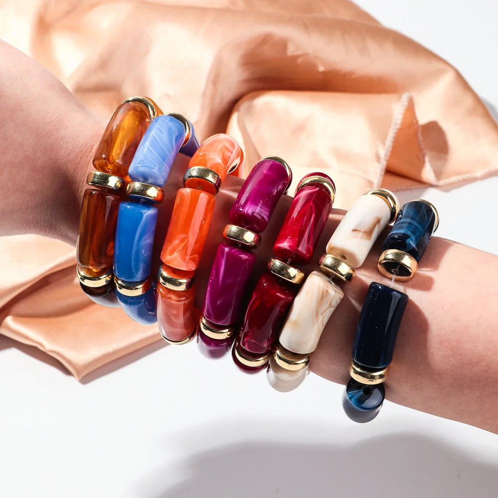 Bamboo tube bead bracelets on wrist in blue, orange, magenta, white, and black tones