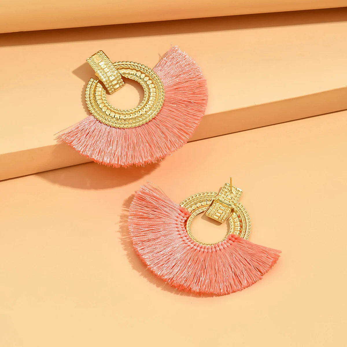 Gold fan stud earrings with coral-pink tassels and circular beaded hoop detail