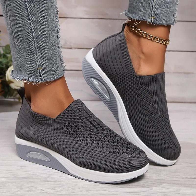 Gray slip-on platform sneakers with knit mesh upper, white outsole and oval cushion detail.