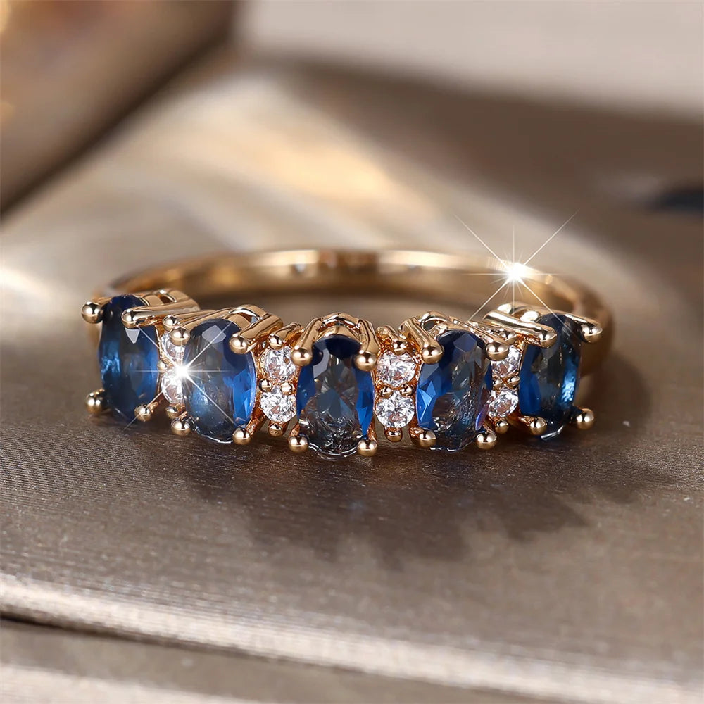 Gold-plated ring with blue oval stones and clear round accents along the band