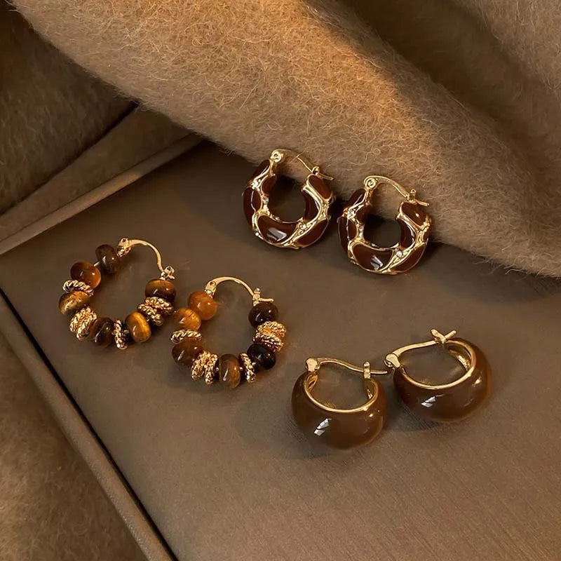 Assorted hoop and beaded drop earrings in a display box, including brown enamel hoops