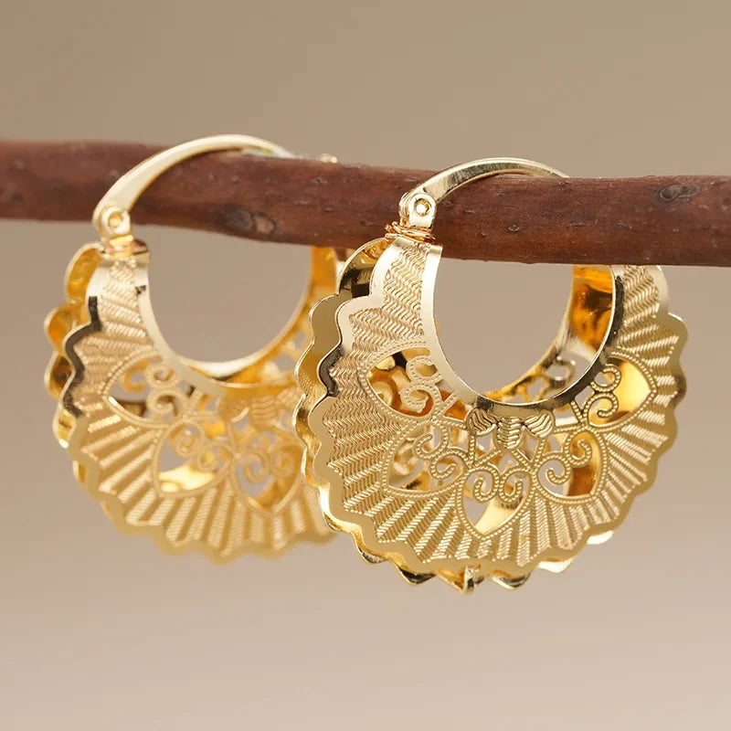 Gold hollow filigree hoop earrings with fan-like scalloped edges and swirl cutouts