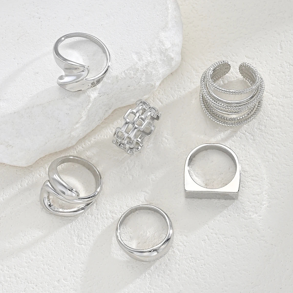 Silver-tone knuckle rings with stacked rows, square charm, and sculpted top ring