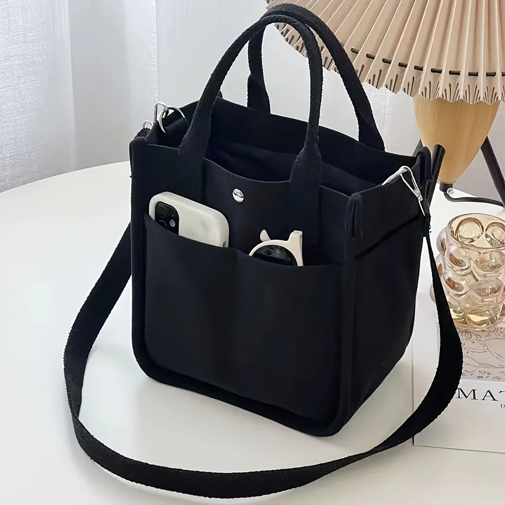 Black canvas tote bag with front slip pockets and adjustable shoulder strap