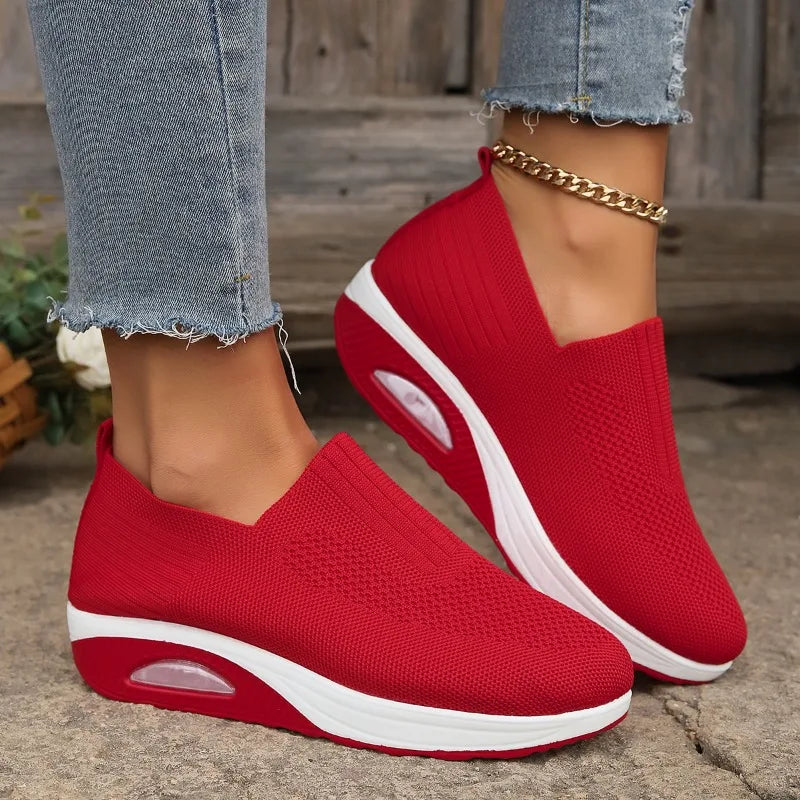 Red slip-on platform sneakers with knit mesh upper, white outsole and oval cushion detail.