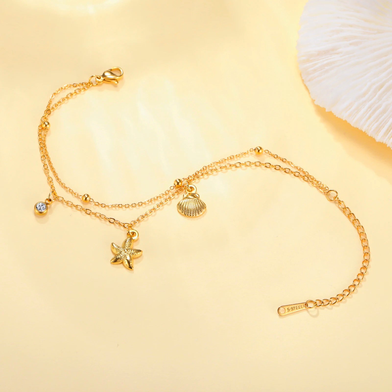 Gold-tone starfish and seashell charm bracelet with round gem accents and tag clasp
