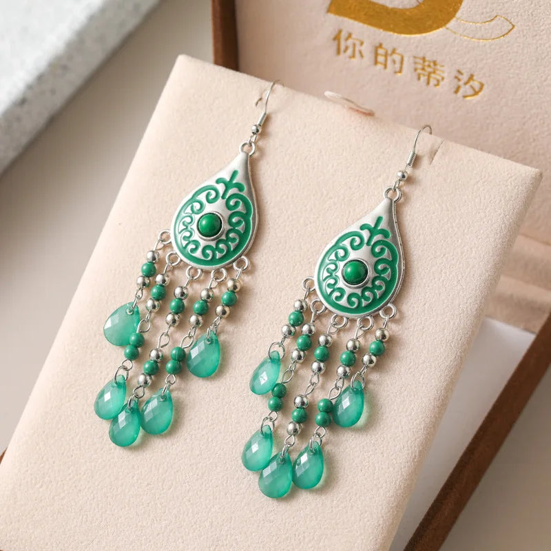 Green teardrop bead tassel dangle earrings with ornate center and silver hooks