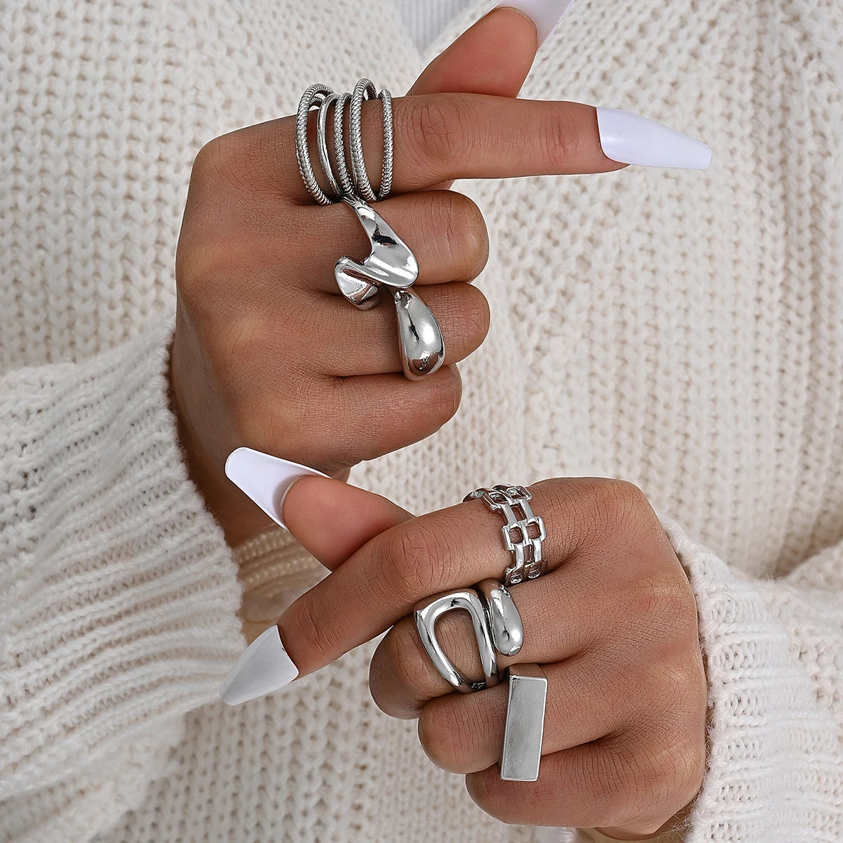 Silver-tone knuckle ring set with stacked bands and a teardrop centerpiece ring