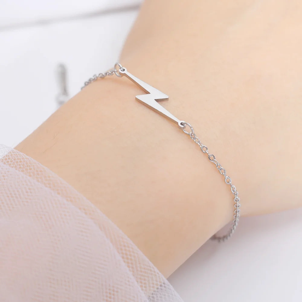 Silver-tone charm bracelet with lightning bolt plate, close-up on wrist
