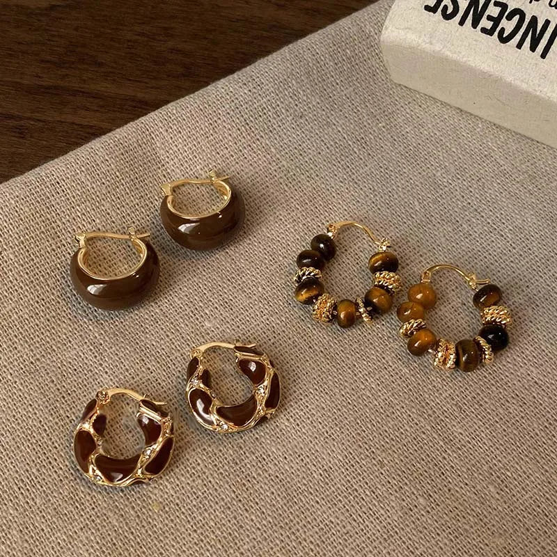 Gold-tone hoop earrings with brown and black bead clusters on display