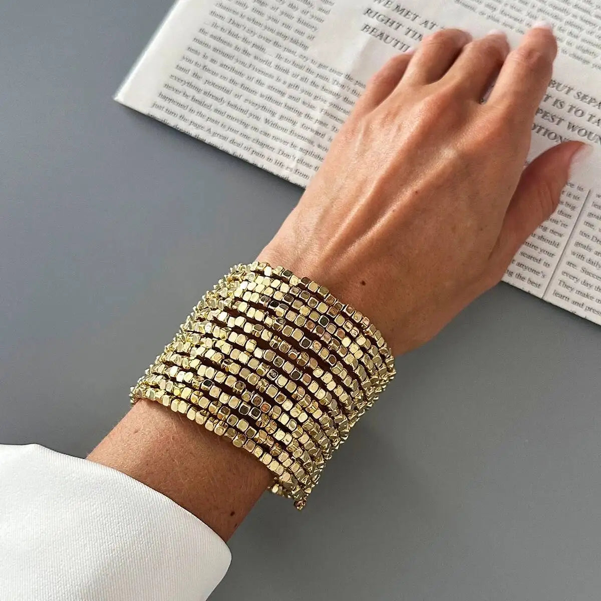 Wide beaded cuff bracelet with gold-tone square beads, layered punk style.