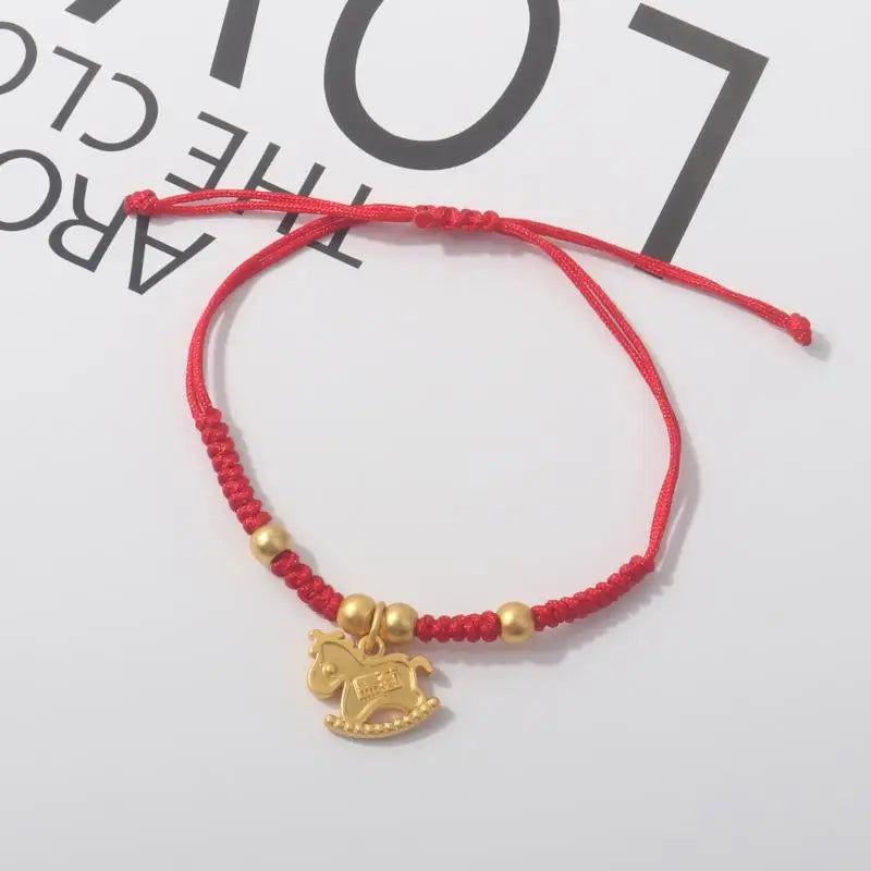 Red rope bracelet with gold beads and a large gold horse pendant