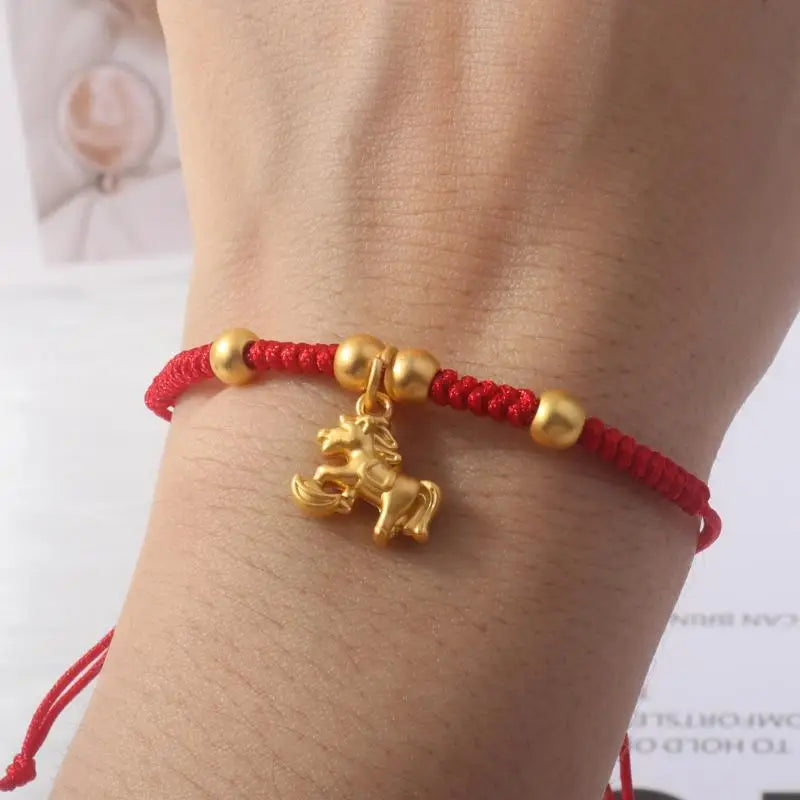 Red rope bracelet with gold horse charm pendant on wrist with gold spacer beads