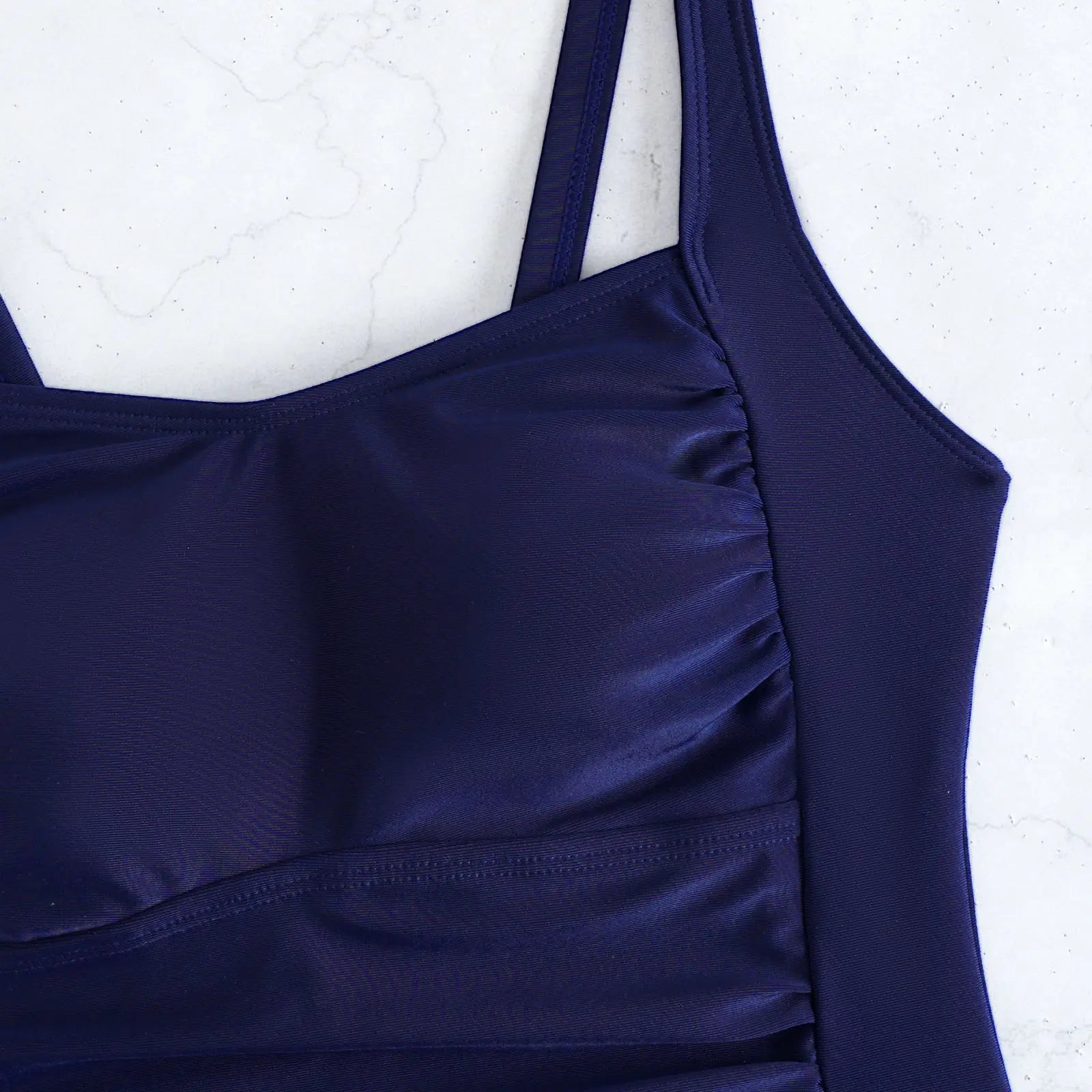 Navy tankini top close-up with ruched front and adjustable shoulder straps.