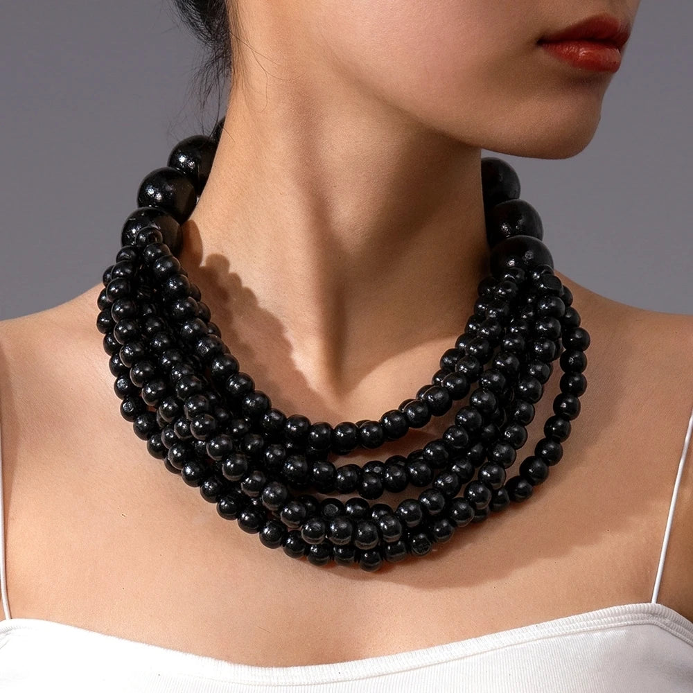 Multi-layer wooden beaded necklace with black round beads worn close to the neck