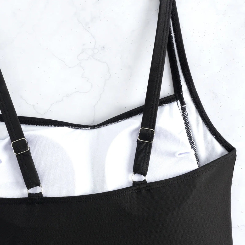Black swimsuit tankini straps and white trim, close-up with attached bra top.