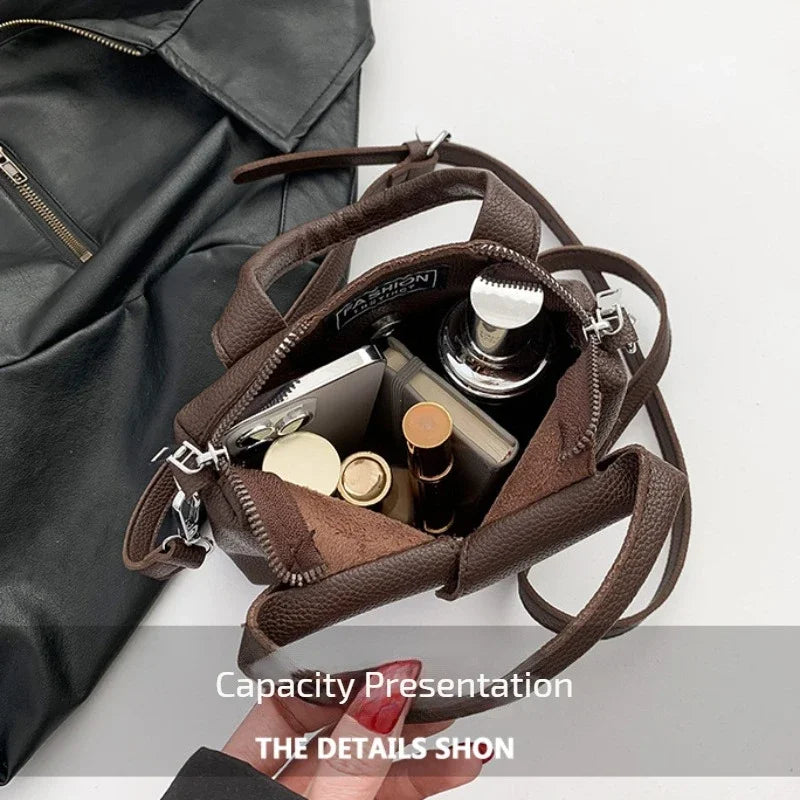 Brown PU leather crossbody bag opened to show small interior items and zipper pocket