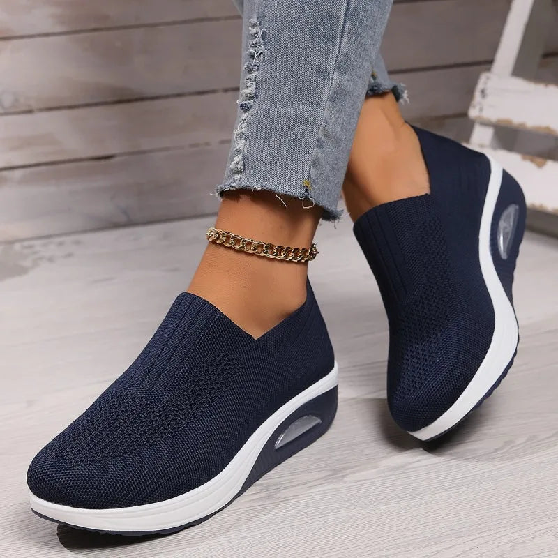 Navy slip-on platform sneakers with knit mesh upper, white outsole and oval cushion detail.