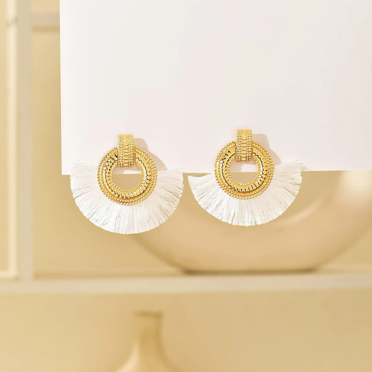 Gold-tone fan stud earrings with round crystal hoop and white tassel fringes