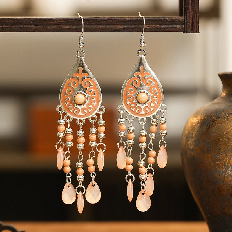Orange teardrop bead tassel dangle earrings with ornate center and silver hooks