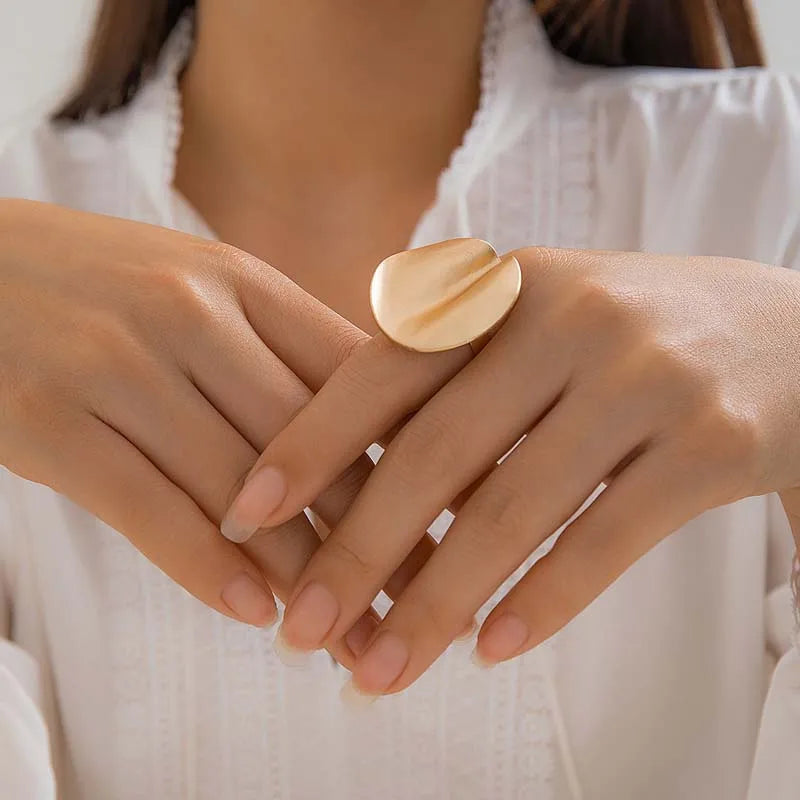 Gold-tone open adjustable ring with smooth oval cuff top, worn on fingers