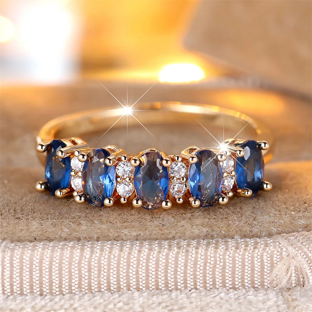 Gold-plated ring with blue oval stones and clear round accents, prong-set band