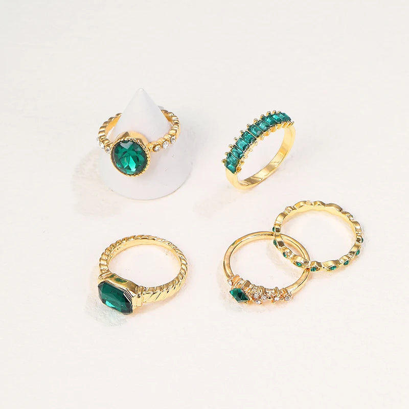 Gold-tone rings with green marquise and oval crystals on white