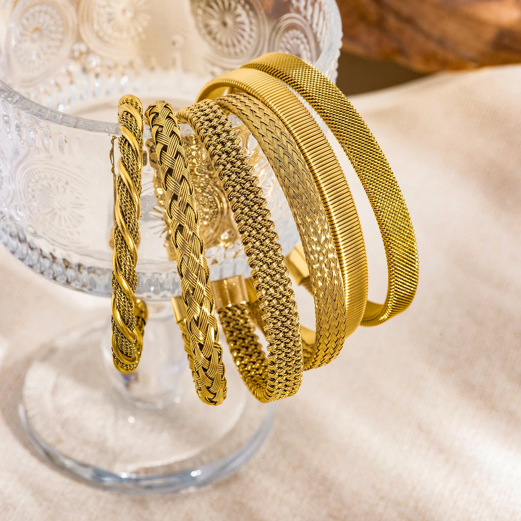 Gold textured open bangle bracelets on display, braided and mesh weave styles