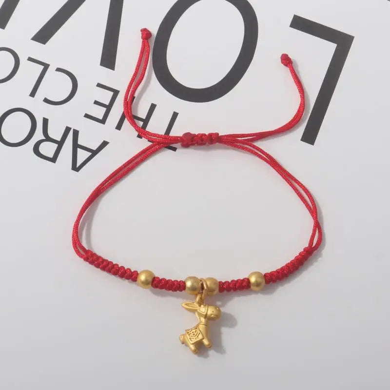 Red rope bracelet with gold beads and small gold horse charm at center.