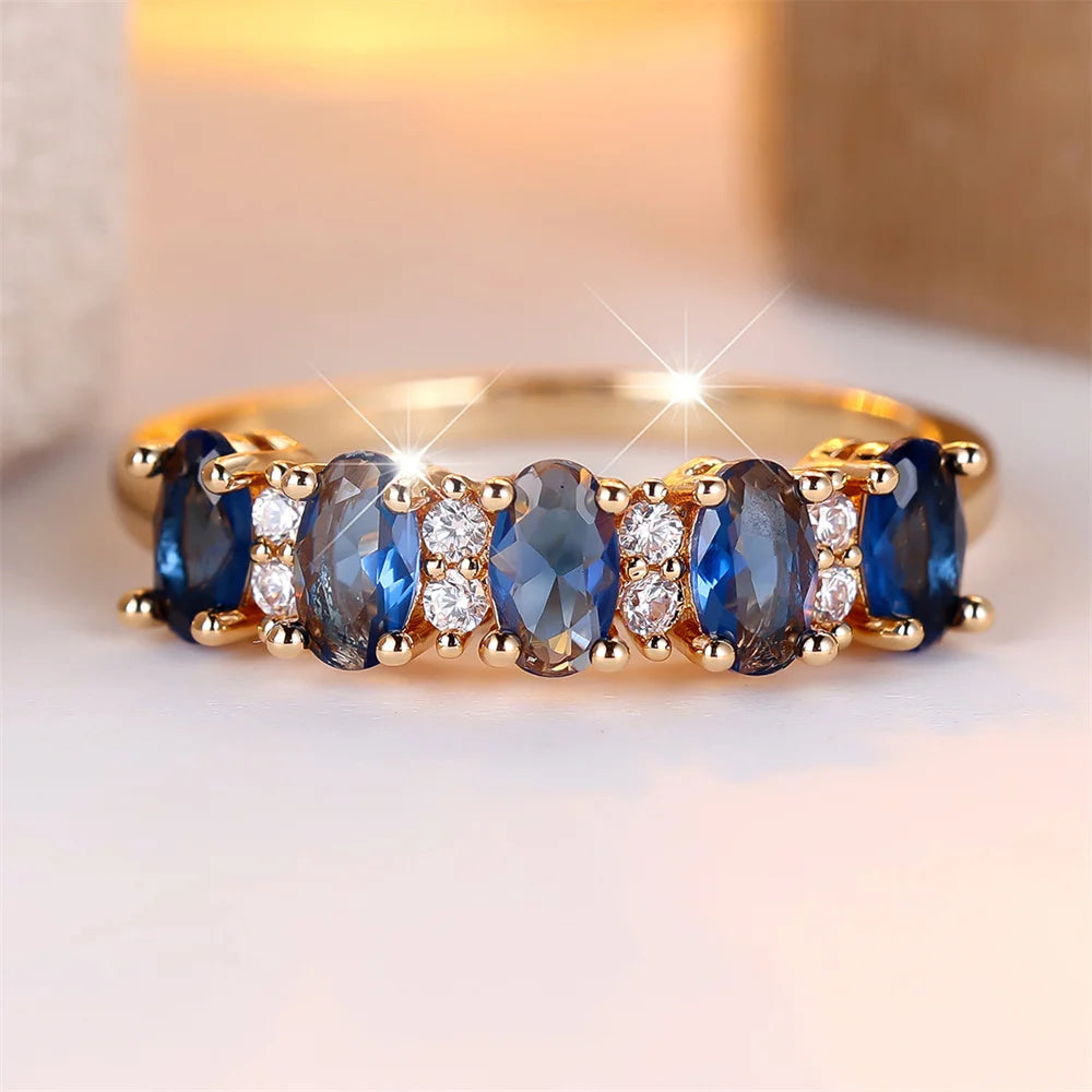 Gold-plated ring with oval blue stones and clear side accents, prong-set