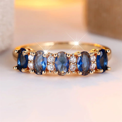 Gold-plated ring with oval blue stones and clear side accents, prong-set