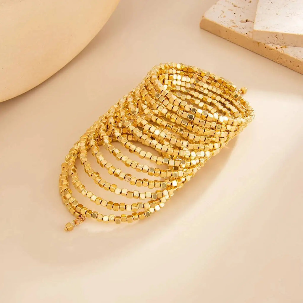 Gold-tone multi-row wide beaded bracelet cuff with square bead accents.