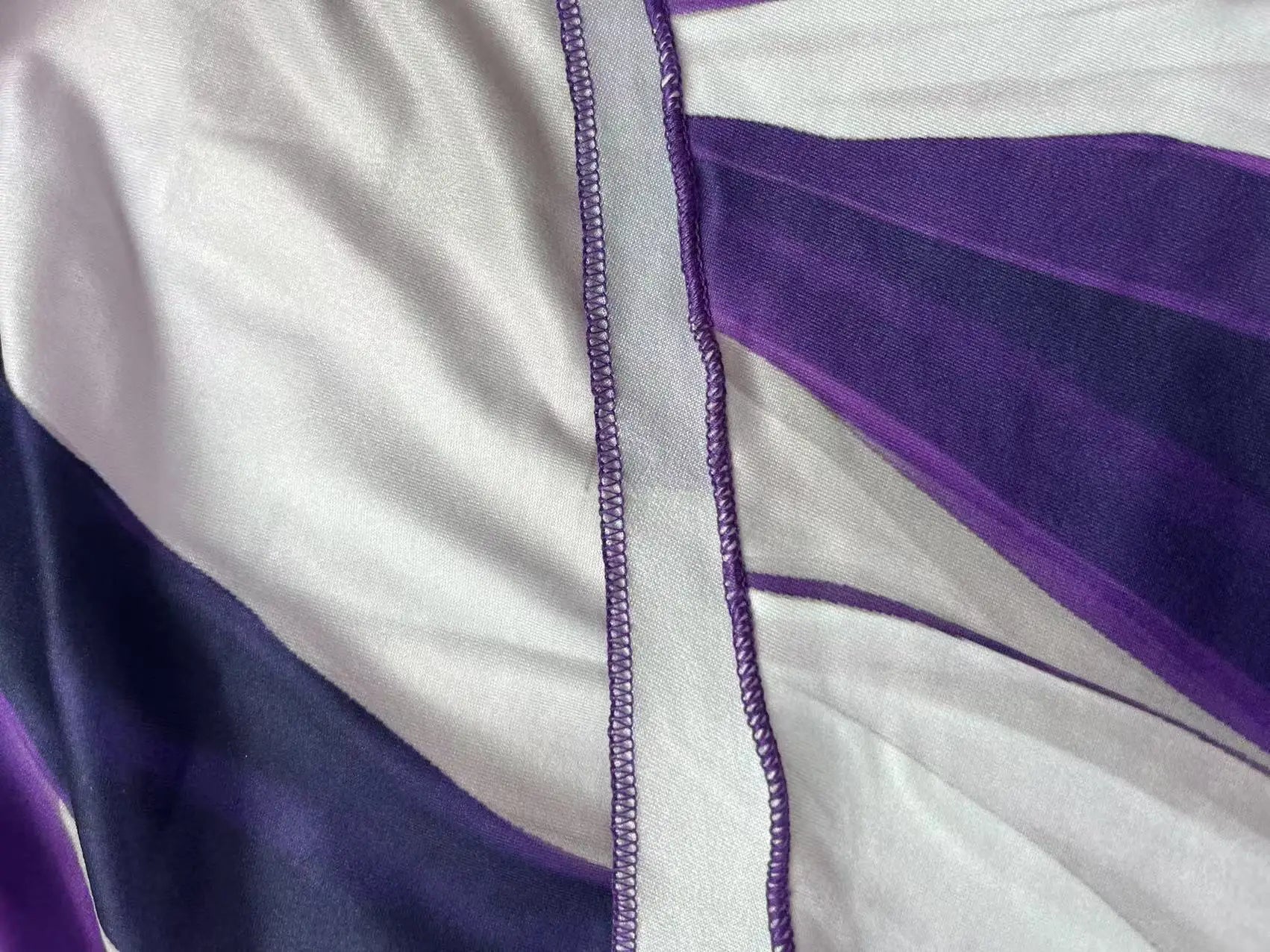 Asymmetrical geometric stripe dress detail with double-strap neckline and purple trim stitching