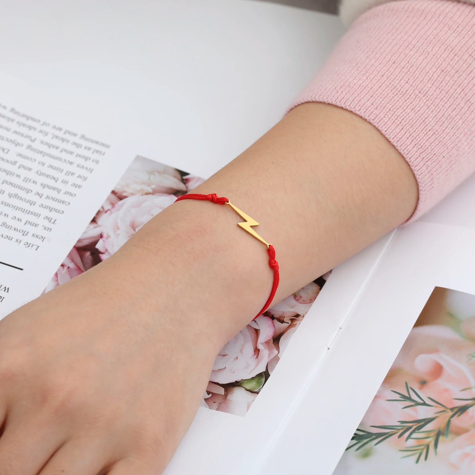 Red cord charm bracelet with yellow lightning bolt on wrist