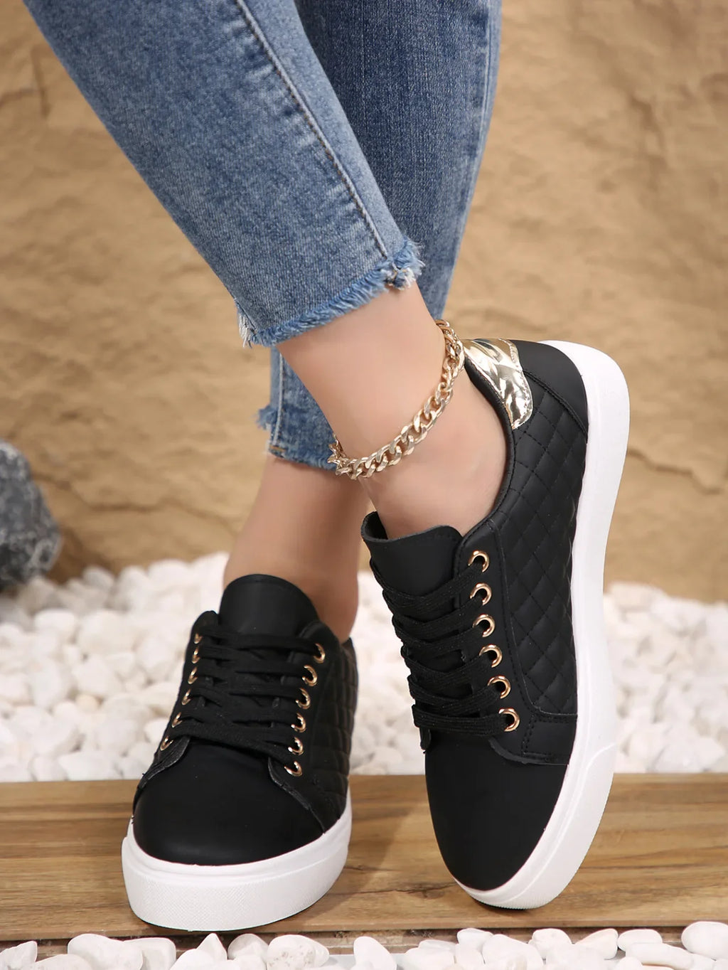 Black quilted lace-up platform sneakers with gold eyelets, front view on feet.