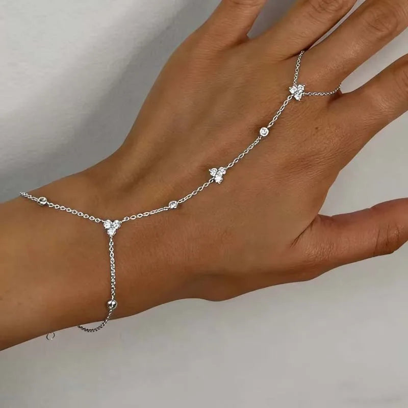 Silver rhinestone flower charm bracelet worn on hand, with linked chain and crystal flower charms