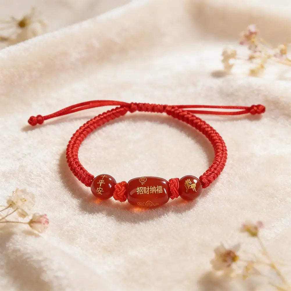 Red braided string bracelet with oval brown bead and small round charm beads