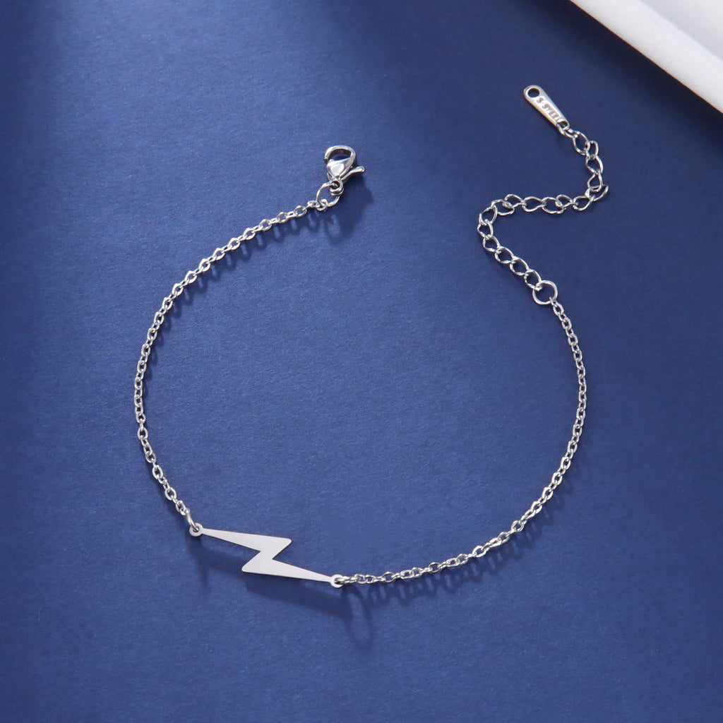 Silver tone lightning charm bracelet with linked chain and white bolt pendant.